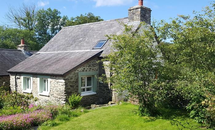 Rear view of Hen Ffermdy cottage with overlooking kitchen windows and rear garden with lawn